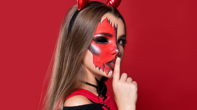 Woman wearing devil costume makeup for Halloween