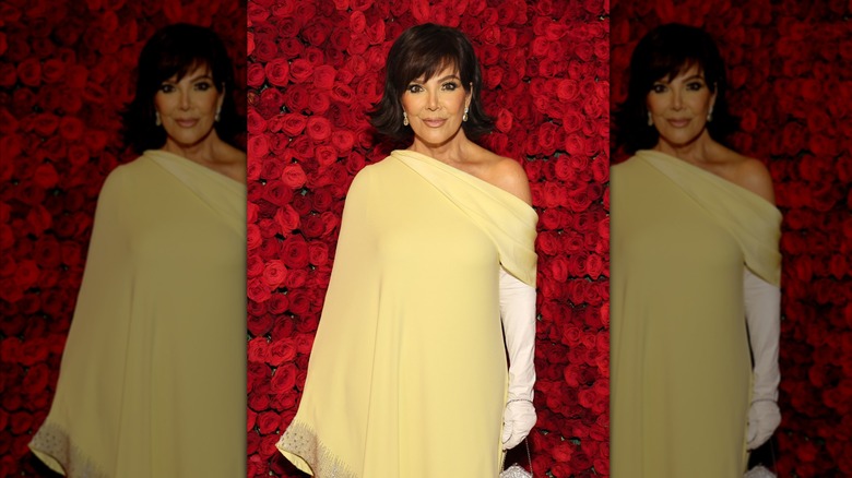 Kris Jenner poses wearing an off-the-shoulder yellow dress and her hair styled into a bob