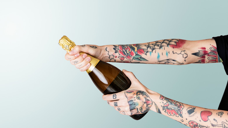 Tattooed person holding champagne