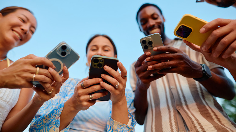 Four young adults operating smartphones