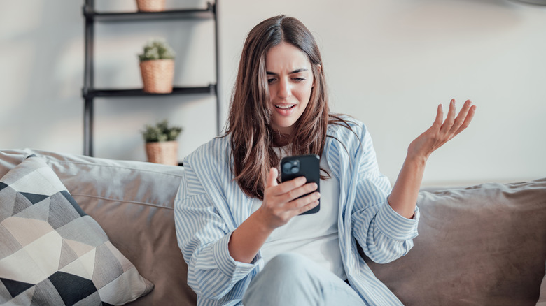 A woman looking at her phone in exasperation