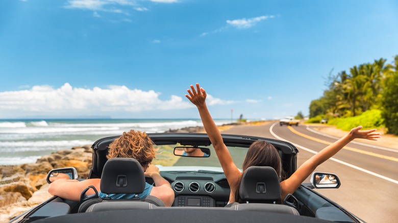 couple driving convertible along coast