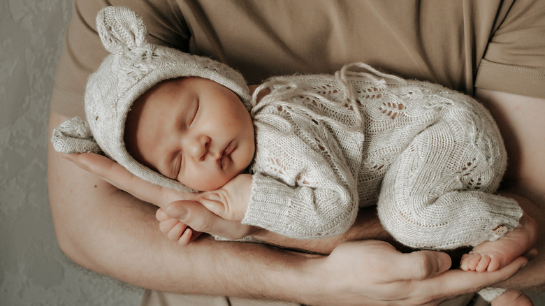 A newborn baby being cradled in someone's arms