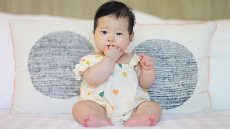 A baby girl sitting on a bed