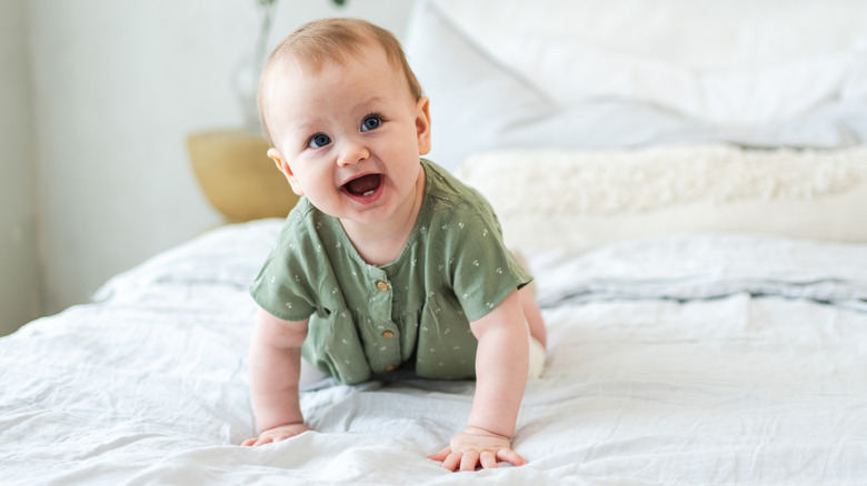 Laughing baby crawling on a bed