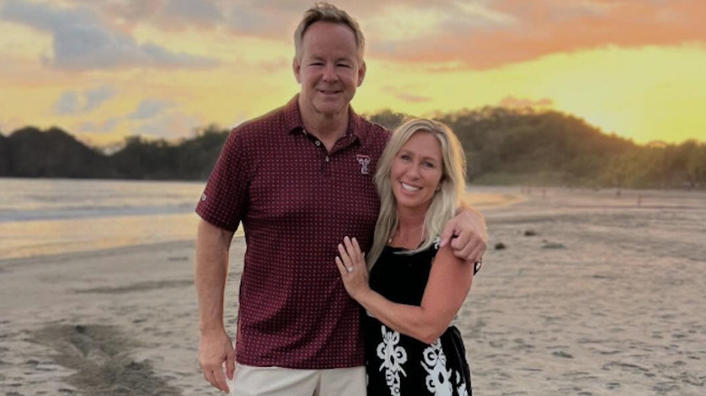 Marjorie Taylor Greene and Brian Glenn pose together on a beach at sundown