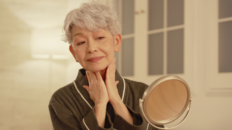 A woman applying cream to her neck
