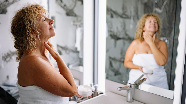 A woman applying cream to her neck
