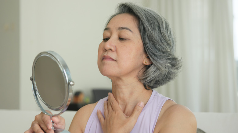 A woman looking at her neck