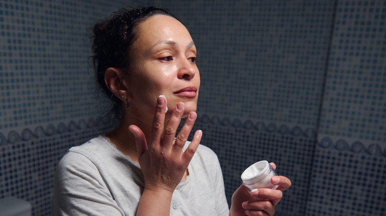 An older woman applying cream to her skin