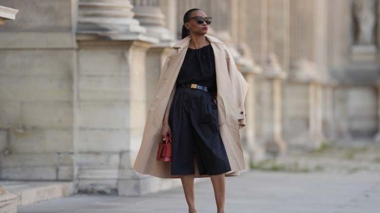 A woman in Paris wearing knee-length shorts and a coat draped over her shoulders