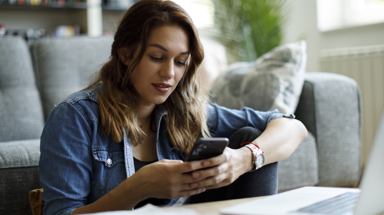 Woman texting by her couch