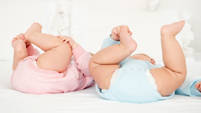 Two baby bottoms in pink and blue diapers