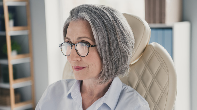 A woman with a gray bob haircut wearing glasses and a collared shirt.