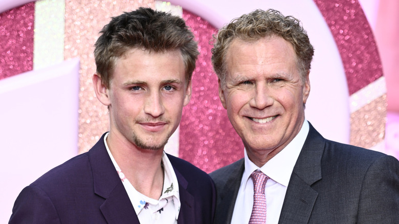 Will Ferrell posing with his son Magnus at a red carpet event with a pink sparkly background.