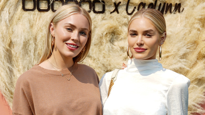 Cassie Randolph and Michelle Randolph pose together in front of a fuzzy golden background.