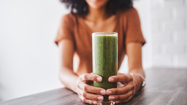 Woman holding green juice glass