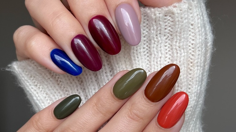 A close up shot of a multicolor manicure with various earthy fall colors.