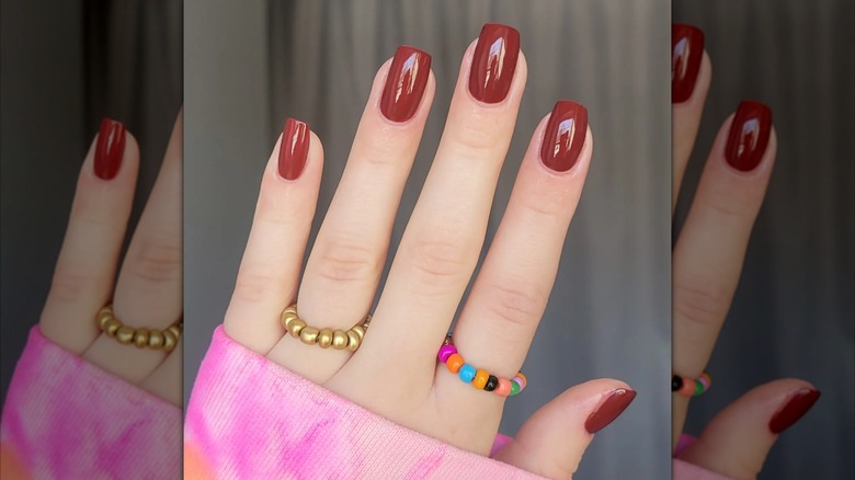 Close up shot of a rust-red manicure.
