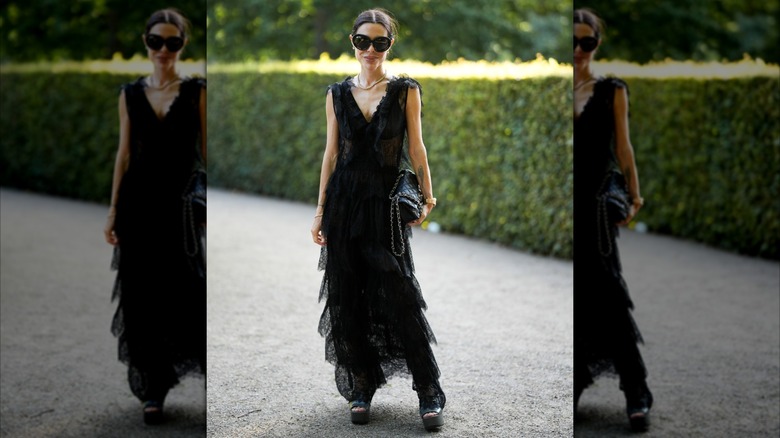 A woman wearing a black lace dress with several layers of ruffles.