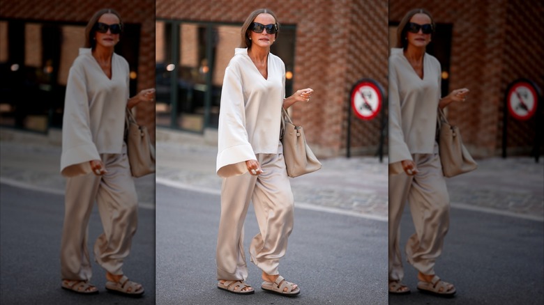 A woman wearing light gray satin trousers.