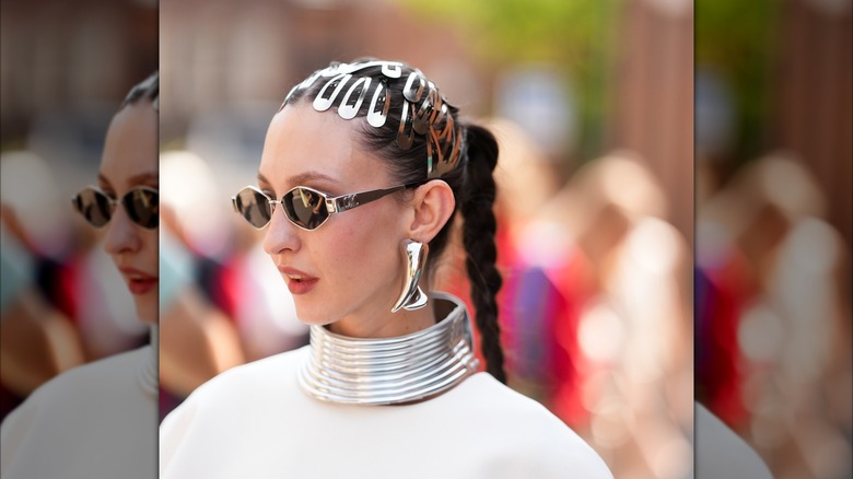 A woman wearing oversized chrome earrings, a choker, and several barrettes.
