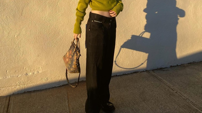 woman wearing black jeans holding floral purse