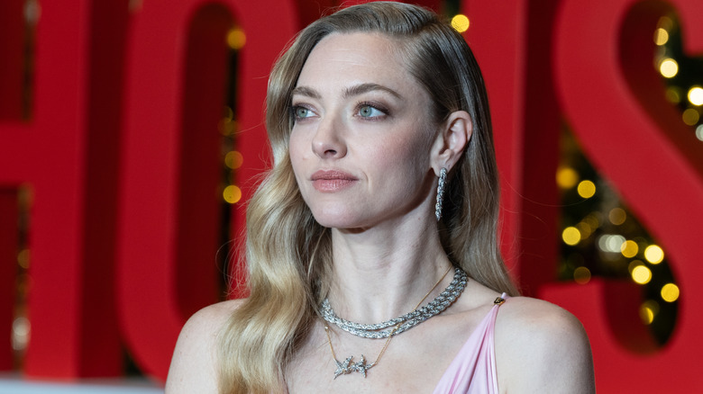 Amanda Seyfried looks to the left wearing wearing two crystal chokers and hoop earrings