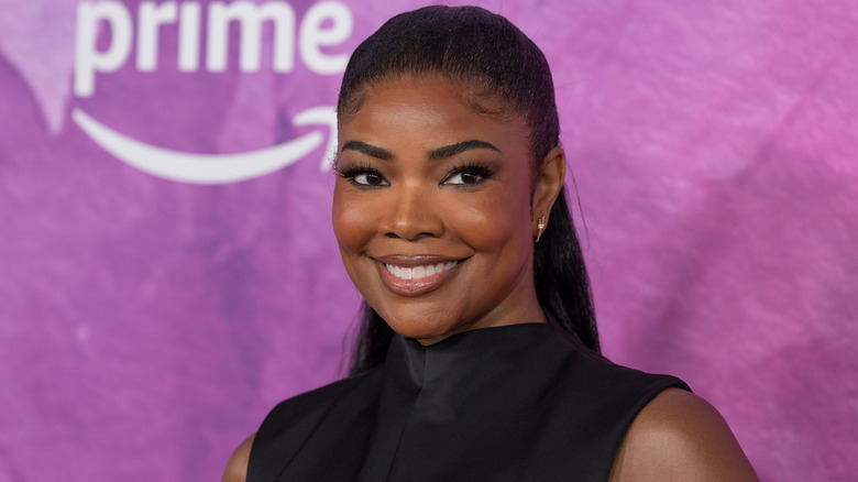 Gabrielle Union smiles wearing a black high-neck top