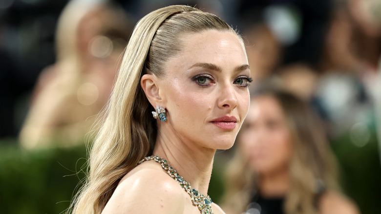 Amanda Seyfried smiles wearing encrusted earrings and a crystal choker