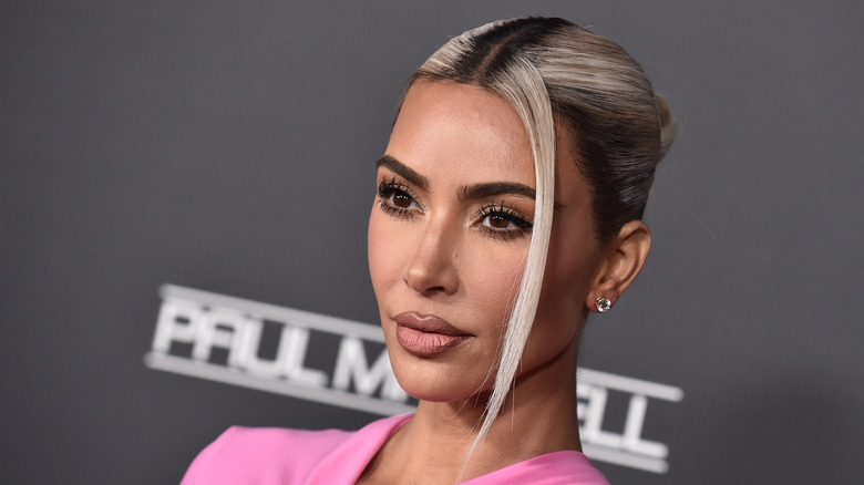 Kim Kardashian poses wearing her blonde hair slicked back and a pink top