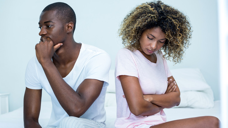 tense couple sitting on bed