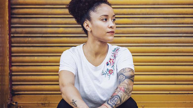 Thoughtful woman with arm tattoos
