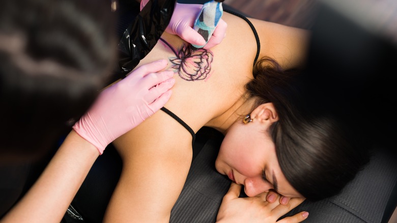Woman getting flower tattoo