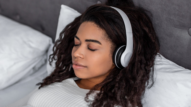 Black woman in bed with headphones