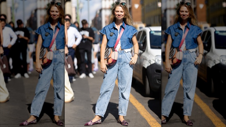 A woman wearing light-wash mom jeans and a cropped denim shirt.