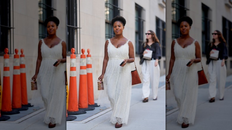 A woman with a white lace dress that has an empire waist