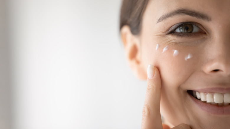 Woman applying eye cream.
