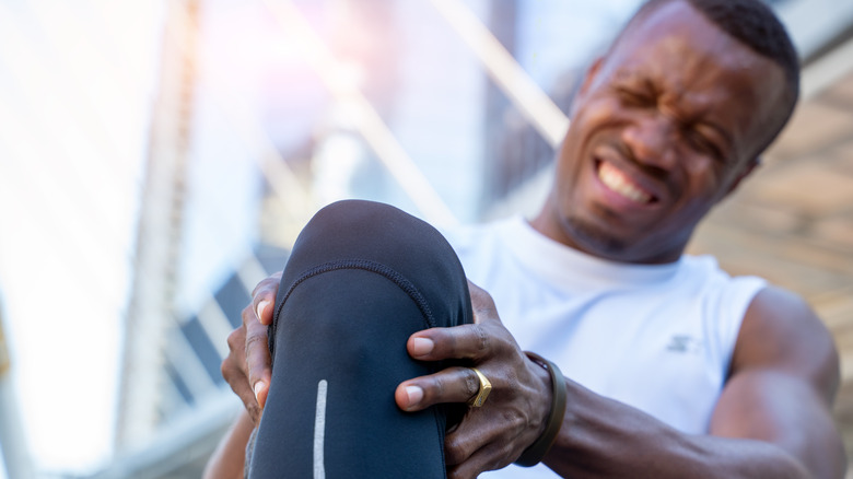 man clutching sore knee