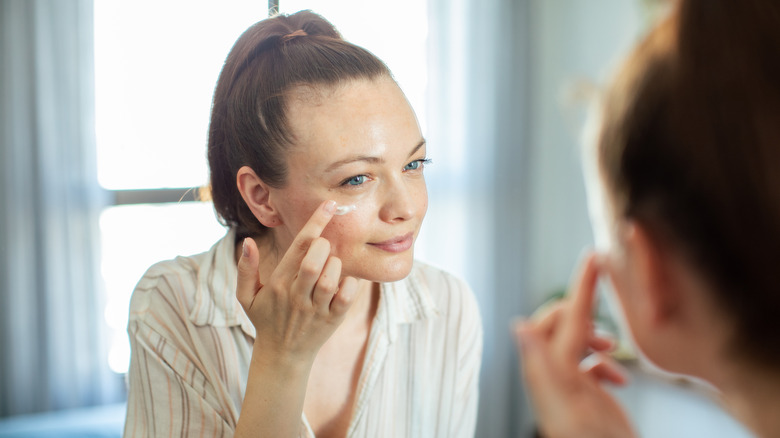 smiling woman applying makeup primer