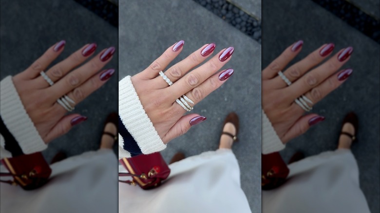 A hand with burgundy chrome nails.