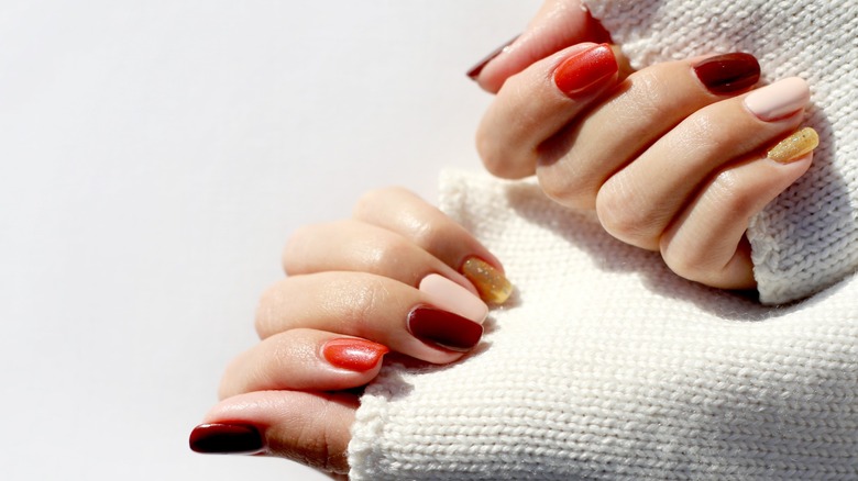 Hands with multi-colored summer-to-fall nail colors.