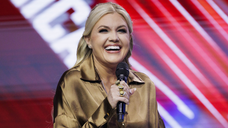Erika Kirk smiles while holding a microphone