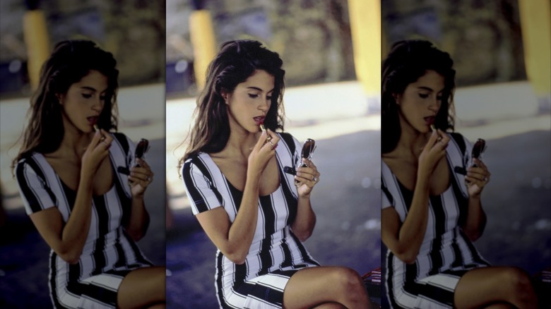 Jami Gertz, applying lipstick, wearing a Moschino stretch dress December 1988
