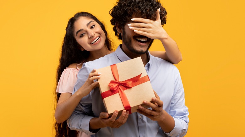 Woman presenting boyfriend with gift for Valentine's Day