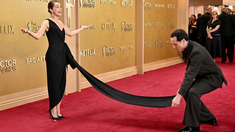 Keri Russell poses on the red carpet while Matthew Rhys fixes the train of her gown