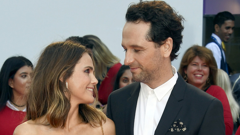 Keri Russell and Matthew Rhys smile while giving affectionate looks to one another at an outdoor red carpet event