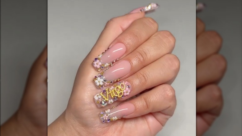 Square manicure with floral decals and the word "Virgo" written in gold