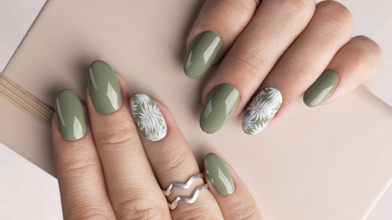 Close up to almond manicure with green nail polish and flower designs