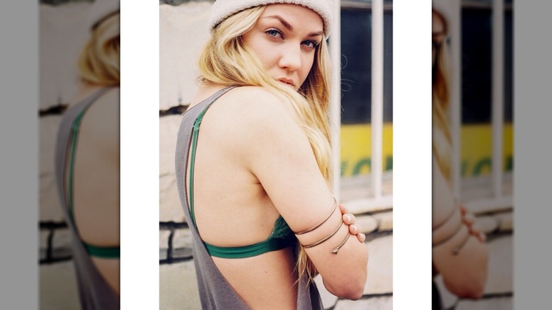 Erika Kirk looking over her shoulder, wearing a beanie and a loose tank top over a green bra